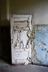 alte Holztüre im Innenraum mit großflächig abblätternder Farbe neben blauer Wand