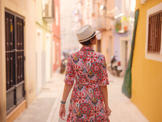 Woman in dress strolls through colorful streets of Spanish coastal town of La Vila Joiosa or Villajoyosa. sunny winter atmosphere highlights charm of Mediterranean architecture and quiet seaside life