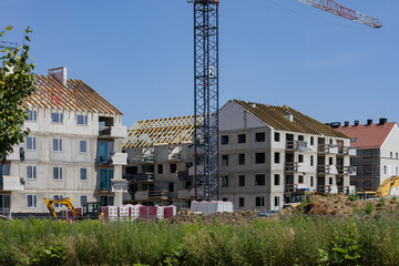 Modern residential apartment buildings under construction with cranes, scaffolding and construction...