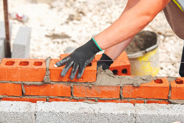 Bricklayer laying red bricks on building site