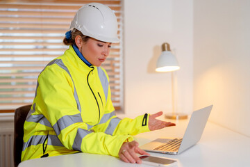 Woman Building Project Manager working in office while using laptop and holding  smartphone