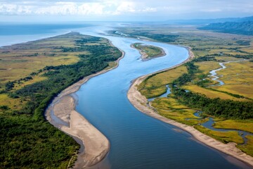 Wide meandering river flowing into the ocean near lush tropical vegetation