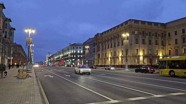 MINSK - MAR 25, 2025: A busy city street at night with cars and pedestrians. The street is lit up with lights from the buildings and street lamps on Independence Avenue
