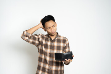 A man wearing a plaid shirt, expressing concern as he looks at his empty wallet, conveying financial strain.