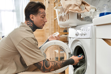 Hands on laundry day for a stylish tattooed man in a cozy home environment
