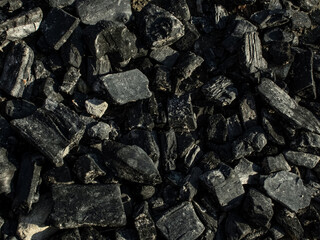 Natural fire ashes with dark grey black coals texture. It is a flammable black hard rock.