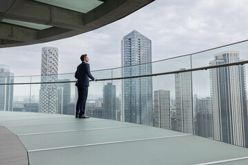 Businessman looking out at City Skyline from High Rise