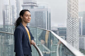 Successful Businesswoman looking out at city skyline from skyscraper office