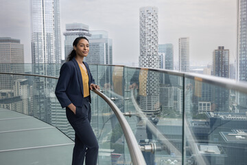 Confident Businesswoman looking out at city skyline from skyscraper office
