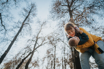 A mother with her baby shares a joyful bonding moment outside in the serene nature of a park with...