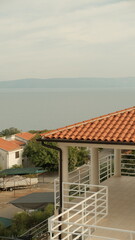 A sunlit terrace overlooks the calm Adriatic Sea, with white railings tracing the clean geometry of the balcony.