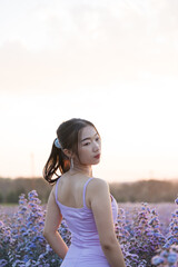 Portrait of beautiful asian girl in violet dress in cutter flower field at sunset sky.