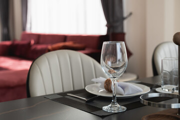 Elegant Dining Table Setup with Glassware and Tableware in Contemporary Interior Design with Plush Seating in the Background