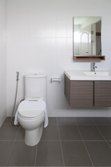Modern and Minimalist Bathroom with White Ceramic Toilet, Wooden Vanity Sink, and Large Mirror in...