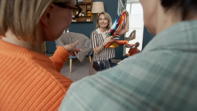 Over shoulder shot of mature Caucasian woman demonstrating colorful silk babushka scarf to her friends
