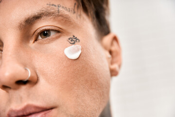 Handsome tattooed man applying moisturizer at home in a cozy and inviting atmosphere