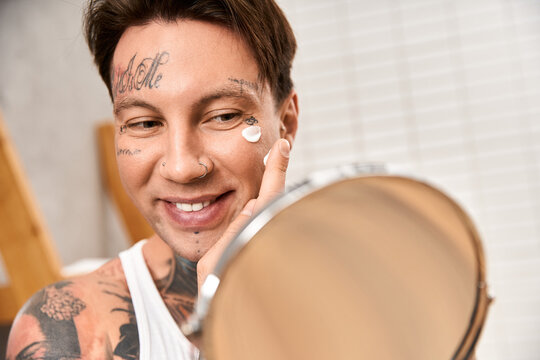 Handsome tattooed man enjoying a cozy morning skincare routine at home