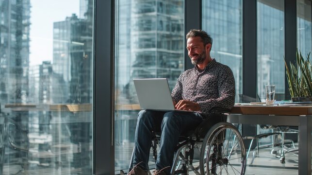 Disability-friendly office setting with professional man in wheelchair using laptop