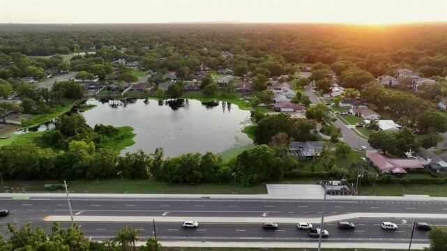Golden sunset in luxury suburb district of american town in Florida. Traffic on main street of road at dusk. Aerial lateral wide shot. Brandon, United States.