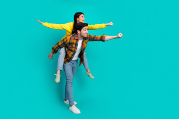 Happy young couple posing playfully against a turquoise background, enjoying fun moments and demonstrating a joyful bond