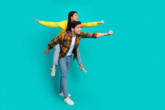 Happy young couple posing playfully against a turquoise background, enjoying fun moments and demonstrating a joyful bond