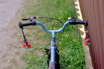 Handlebars of a colorful bicycle resting on a grassy path beside a wooden fence