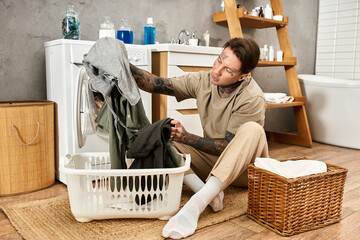 Handsome tattooed man enjoys cozy moments doing laundry at home in a stylish environment