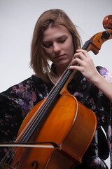 Woman playing cello, wearing floral kimono, close-up.