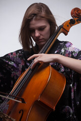 Woman playing cello, wearing floral kimono, close-up.