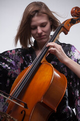 Woman playing cello, wearing floral kimono, close-up.