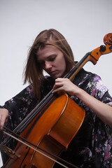 Woman playing cello, wearing floral kimono, against white background.