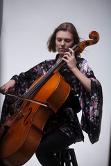 Woman playing cello, wearing floral kimono, studio shot.