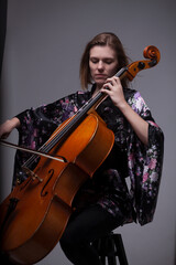 Woman playing cello, wearing floral kimono, studio shot.