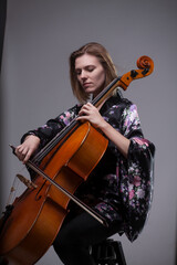 Woman playing cello, wearing floral kimono, studio shot.