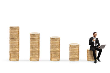 Successful businessman with a laptop computer sitting on a pile of coins