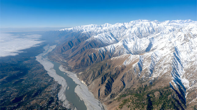 Breathtaking aerial view revealing majestic snow-capped Himalayan peaks, a winding river through the valley, and low clouds adding mystique in Chitral, Pakistan