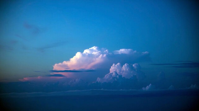 Majestic cumulonimbus clouds glow with soft pink and white hues against a deep twilight blue sky creating a serene and ethereal atmospheric landscape