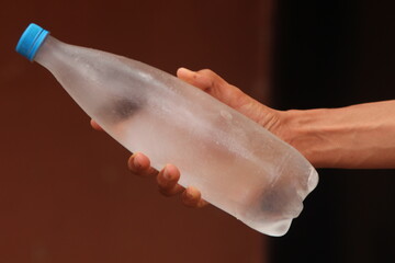 Hand holding a bottle of frozen water