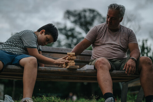 A father and son enjoying a game together on a park bench, emphasizing family bonding and leisure time outdoors.