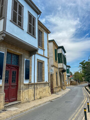 Charming narrow street lined with historic stone houses featuring wooden shutters and balconies in the old town of Nicosia, Cyprus.