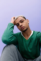Trendy young man with dyed hair displays unique fashion on a vivid purple backdrop