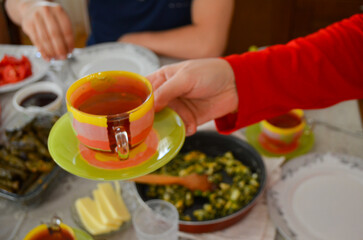 A person is holding a cup with a yellow and red striped handle. The cup is on a green plate. The...