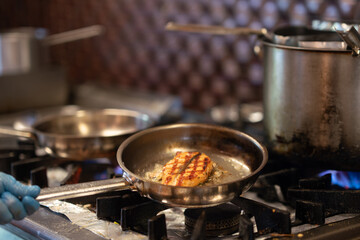 Chef is frying fish in cooking pan.