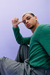 Young man showcases stylish fashion against a vibrant purple background