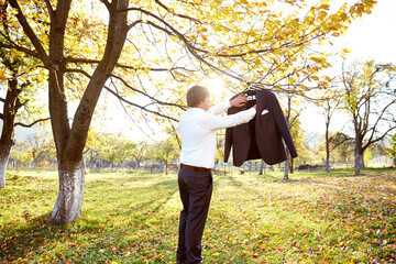A man is hanging his jacket on a tree branch in a park