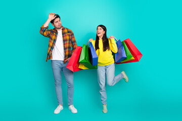 Happy couple holding colorful shopping bags against a turquoise background illustrating shopping...