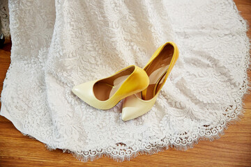 A pair of yellow and white shoes are on a white lace dress