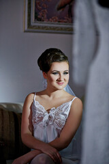 A woman in a white dress is sitting on a couch