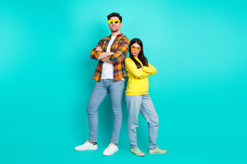 Young Couple in Casual Fashion Posing Confidently on a Teal Background for Lifestyle Advertising