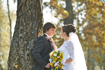 A man and woman are standing under a tree, the man is wearing a suit